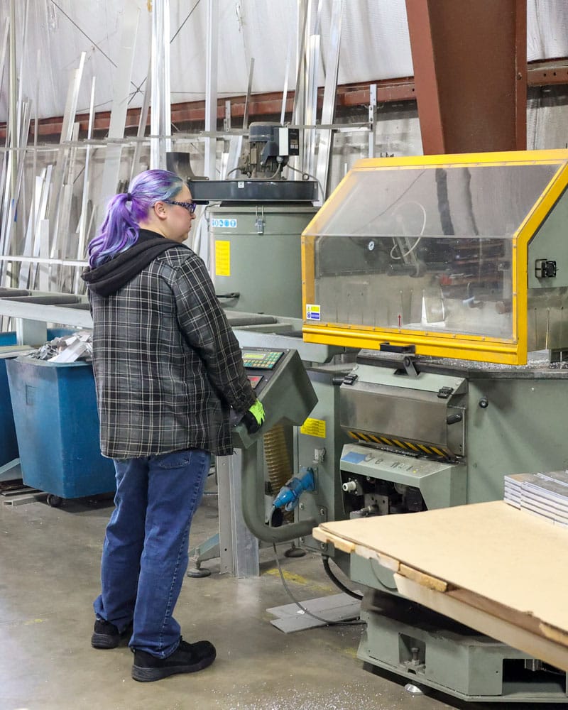 Americlad Employee Working With Machine Behind Safety Shield