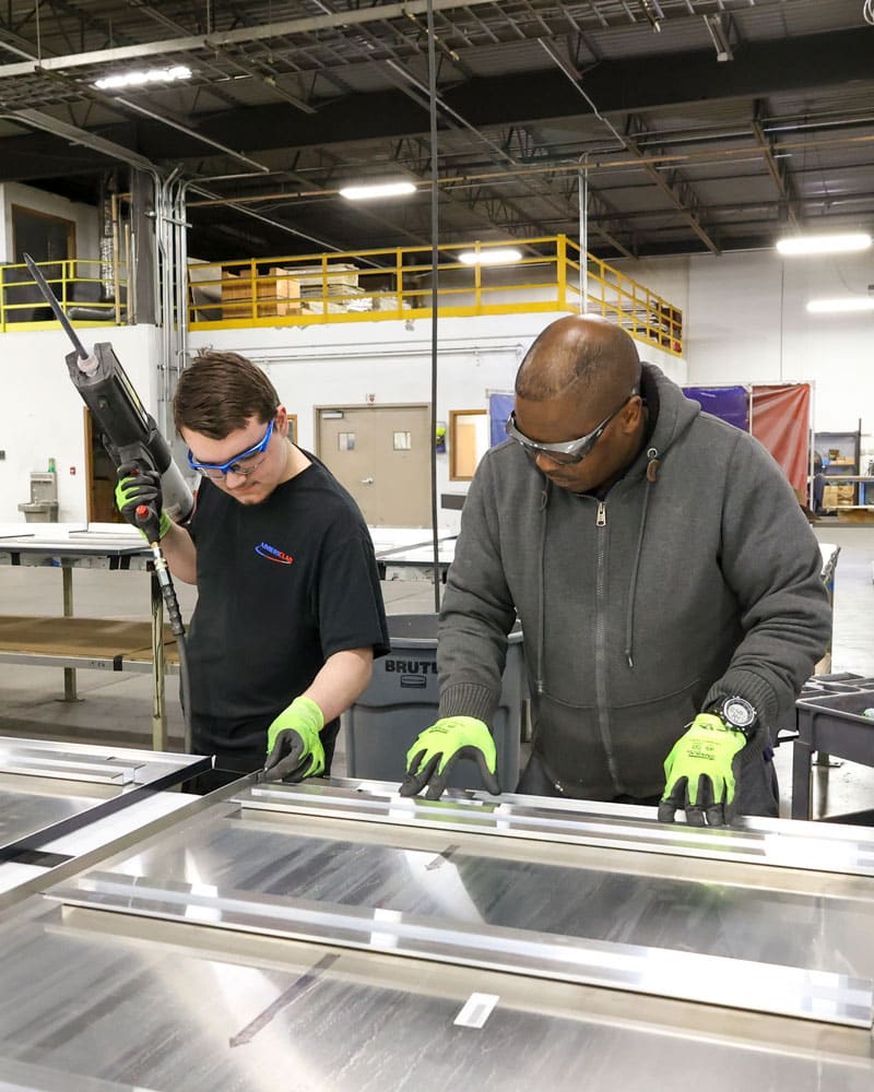 Employees Reviewing Metal Panel Alignment